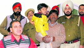 The boy, who was kidnapped on Sunday, in the lap of his father in Ludhiana on Monday.