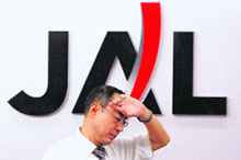 An employee of Japan Airlines works in front of its logo at Haneda airport in Tokyo on Tuesday.
