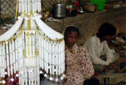 An impoverished family sits in its shack with a chandelier displayed besides it.