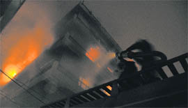 ADFO Kartar Singh manually sprinkles water due to the absence of hydraulic ladder while fighting flames in the five-storeyed building in Ludhiana on Monday night.