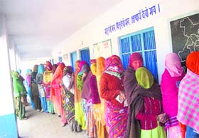Veiled women wait in a queue to cast their vote in a village in the Ellenabad assembly constituency