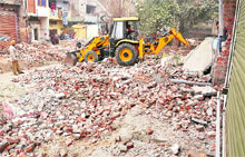 A JCB machine demolishes shops in Jawahar Nagar Camp in Ludhiana on Thursday.
