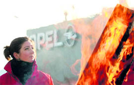 A woman stands behind wooden pallets set on fire as Opel trade union members blocked access for car parts to be delivered to the company assembly plant of Antwerp on Friday. General Motors has dropped the axe on its Opel assembly plant, shedding 2,600 workers under sweeping cuts to labour and capacity across its European sites. 
