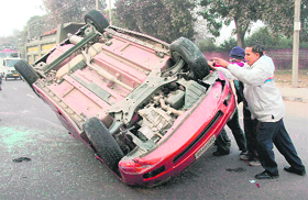 Policemen lift a car that overturned after an accident at Industrial Area, Phase I,in Chandigarh on Friday. 