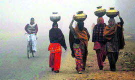 Women on their way to fetch water on a foggy morning in Hisar.