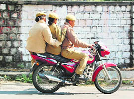  Cops violating traffic rules by driving without helmets and also by triple riding at Dharamsala on Sunday.