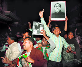 Cheering supporters carry a portrait of the country's independence leader Sheikh Mujibur Rahman outside the Dhaka central jail on Thursday