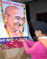 A student offering flower petals on the portrait of Mahatma Gandhi during a function at Abohar