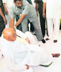 Andhra Pradesh Chief Minister K Rosaiah is helped by a security personnel after he loses his balance during a function in Hyderabad on Saturday.