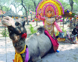 A folk dancer from West Bengal rides a camel during the inauguration of the 24th Surajkund Crafts Mela in Faridabad.