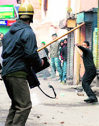 A protester throws a stone at a policeman in Srinagar on Monday