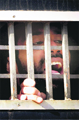 A detained American Muslim shouts We are being tortured from a prison van as he leaves after appearing in an anti-terrorist court in Sargodha on Tuesday.