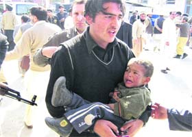 A man carries an injured boy from the site of a bombing near a school in Timergara, the main town in Lower Dir district in Pakistans restive North-West Frontier Province