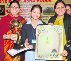 Asha Hooda presents a trophy to Srishti of Dyal Singh School during an awareness programme in Karnal on Friday.