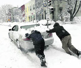 People help push a car stuck in the snow in Washington on Saturday. A huge blizzard dumped a blanket of thick snow over the US east coast, paralysing the region and snapping power lines.