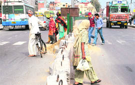 Pedestrians risk their lives while crossing a road divider in Lalru.