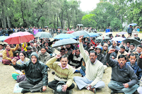 Ministerial services employees continue their protest despite rain at the Gandhi Park in Dehradun on Monday.