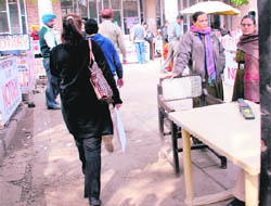 A woman carrying a file and a handbag goes past female security personnel unchecked as she is wearing a black coat at the district courts complex in Chandigarh. 