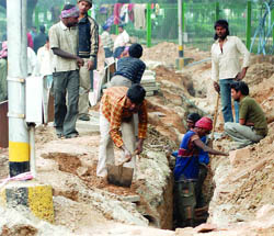 Labourers at work on the road near the office of Commonwealth Games-2010 at Jantar Mantar in New Delhi on Sunday.