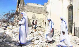 Nuns belonging to the Missionaries of Charity order stand next to the earthquake-damaged national cathedral in downtown Port-au-Prince on Saturday.