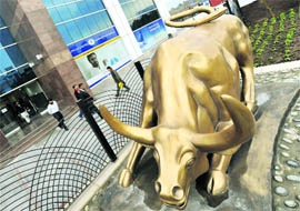 Pakistani investors walk past the bronze bull statue outside the Islamabad Stock Exchange building in Islamabad on Monday.