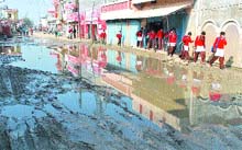 School students pass through sewege-filled streets of the Shivpuri Mohalla in Phagwara.