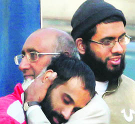 A man identified as Umar Farooq (left), who the police says is one of five Americans accused of planning terrorist attacks inside Pakistan, hugs his father Khalid Farooq as fellow American detainee Waqar Hussain Khan looks @@on before a court appearance in Sargodha