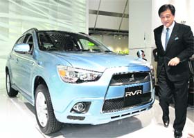 Japan's auto giant Mitsubishi Motors president Osamu Masuko walks past the new compact sports utility vehicle (SUV) "RVR", equipped with a 1.8-litre engine, at its launch in Tokyo