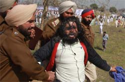 Policemen whisk away an unemployed linemen, who tried to disrupt the foundation stone laying function of a college, at Ghudda village near Bathinda on Sunday. 