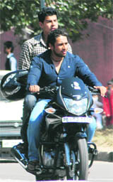Unmindful of their safety, youngsters ride a motorcycle with helmet hanging by the side. 
