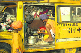 A devotee prepares food inside his car home parked in front of a gurdwara in Gurgaon