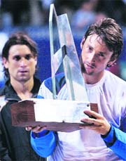 Juan Carlos Ferrero holds up the champions trophy as David Ferrer (L) watches after their final at the ATP Buenos Aires Open on Sunday.