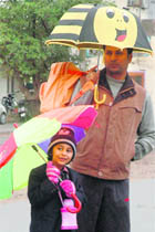 A child with his father, waits for his school bus during light showers in Sector 45, Chandigarh, on Tuesday.