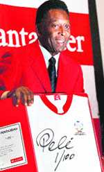 Soccer legend Pele poses with a shirt with his signature during a news conference in Mexico City