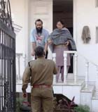 A police officer questions the inmates of an ashram on the whereabouts of their guru in Gurgaon on Thursday.