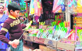 A boy sizes up a pichkari for the coming festival of Holi in Jammus Kanak Mandi.