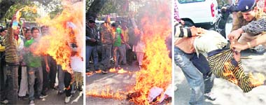From left: A Samajwadi Yuwjan Sabha worker pours petrol on the effigy of the Union Finance Minister in Dehradun on Sunday; the youth catches fire and party workers and a policeman remove his sweater