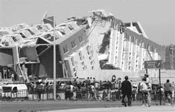 Residents look at a collapsed building in Concepcion, Chile, on Saturday