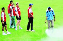 Brett Lee with other players of Kings XI Punjab look at a worker spraying pesticide at PCA Stadium, Mohali, on Wednesday.