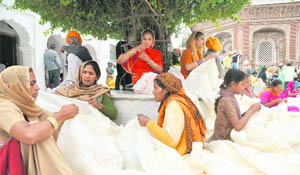 Devotees from Punjab stitch covers for the Jhanda Sahib on the eve of the Jhanda Mela at Guru Ram Rai Darbar in Dehradun.