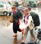 Two foreigners come out of the railway station in the rain in Jalandhar on Thursday. 