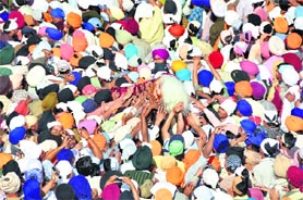 Devotees raise the Jhanda Sahib at the Jhanda Mela at Guru Ram Rai Darbar Sahib in Dehradun on Friday. 