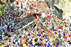 Devotees raise the Jhanda Sahib at the Jhanda Mela at Guru Ram Rai Darbar Sahib in Dehradun on Friday. 