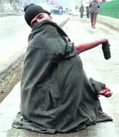 A handicapped beggar looks for alms on a roadside in Srinagar.