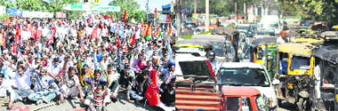 Oblivious of the inconvenience caused to road users, protesters squat at Bharat Nagar Chowk during a satyagraha by trade unions; and (right) chaos on city roads due to the protest in Ludhiana