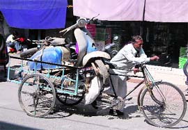 A rickshaw puller takes away an old Lambretta scooter in Dehradun on Saturday