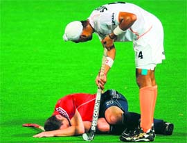 Indias Sandeep Singh (R) checks on injured English player James Tindall in New Delhi on Saturday.