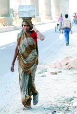 A woman carries bricks at a construction site on the eve of International Women's Day. The day provides an opportunity to communities to recognise and celebrate local womens achievements and the contribution they make to their area.