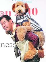 Owner Yoshihiro Nomura holds one-year-old male standard poodle 'Cream' on his back during a dog fashion show at the Aqua City in Tokyo on Sunday.