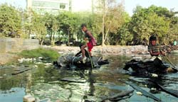 Two boys ply their makeshift boats in stagnant water in Gurgaon
